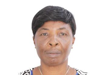 Portrait of a woman facing the camera, short black hair, wearing a patterned blouse and a gold necklace.